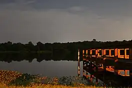 Night view of lake dock illuminated by full moon and streetlight