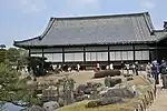 Wooden building with a large hip-and-gable roof and white walls.