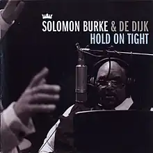 A black-and-white photograph of Burke singing into a microphone