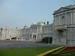 A large palace built of white stone in neo-baroque style. The facade is adorned with colons.