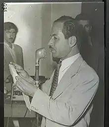 Photograph of Ahmad Hardi reading from a piece of paper