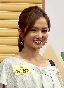 A close-up headshot of a young Asian woman smiling, wearing an ornate crown