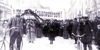 Photograph of a group of women surrounded by policemen during a women's suffrage demonstration in Vienna