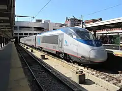 Stainless steel passenger trainset with a blue roof and a thin red sill stripe