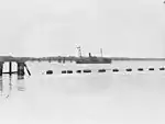 Anti-submarine boom gate in open position (foreground) and permanently anchored ship "HMAS Kinchela" (background). 1943.