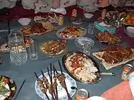 Pashtun dinner sitting on dastarkhan in Helmand Province of Afghanistan, with U.S. troops in the background