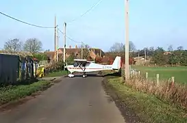 A light aircraft crossing the road between the airfield and farm