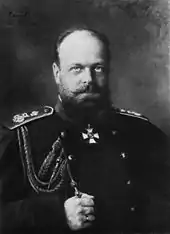 A stocky, balding man with a beard, wearing a dark military uniform.