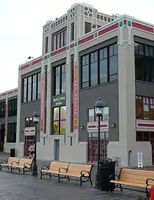 Tall modern building with big windows. Benches are in front.