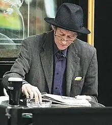 Alex Higgins sitting at a table reading a newspaper