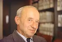 Balding man, with bookshelf in background