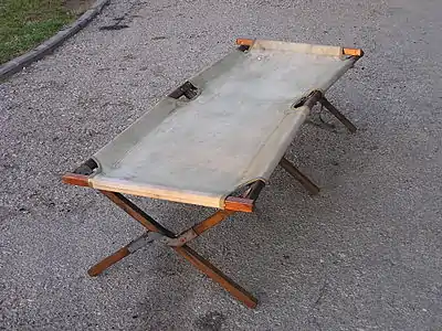 A mid-20-century folding camp bed, wood, cotton duck, and metal