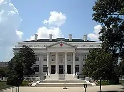 Exterior photograph of the American Red Cross Headquarters, a large, white, columned structure with red crosses on the portico peak and above the main door.