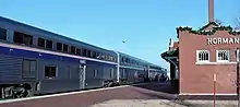 Tall silver coaches with brick building at right