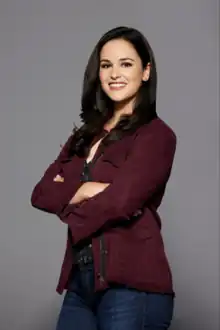 Melissa Fumero smiling as Amy Santiago in a Brooklyn Nine-Nine promotional picture