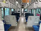 The interior of a train carriage with blue fabric and vinyl seats and large windows