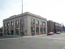 A two-story, white building with large windows at the corner of two streets.