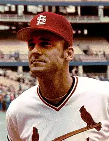 A man in a white baseball uniform and red cap.