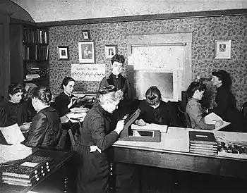 Photo of Harvard computer working in the room. This was taken in 1891. From left to right: possibly Mabel Stevens, unknown woman, Antonia Maury, possibly Evelyn Leland (seated), Williamina Fleming, unknown woman, unknown woman, probably Florence Cushman. This description is based on http://hea-www.harvard.edu/~fine/Observatory/eleland.html#ComputersWithoutPickeringWiki