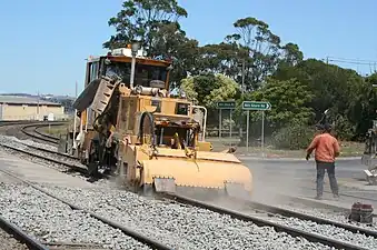 Levelling the ballast height between the rail