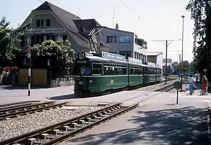 Green tram crosses street