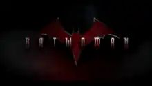 "BATWOMAN" written in a metallic font over a dark background with a red and orange bat symbol in the background.