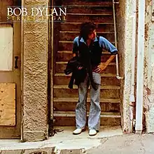 Dylan standing, slightly bent at the waist, in front of a stairwell