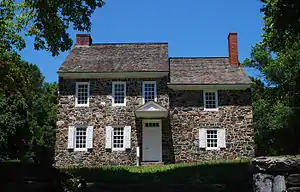 Photo of a two-story stone house with a slate roof