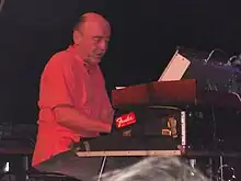 Martin Kratochvíl sitting behind keyboards, wearing a red short-sleeved shirt