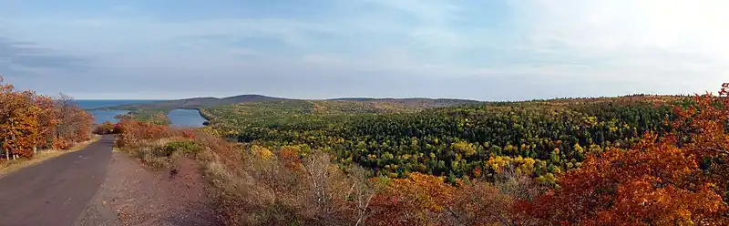 An autumnal panorama from the top of Brockway Mountain with Lake Fanny Hooe and Lake Superior in the distance and Brockway Mountain Drive descending the hill