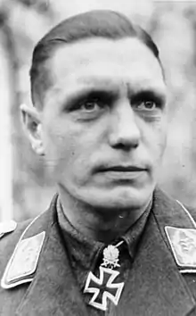 A man wearing a military uniform with an Iron Cross displayed at the front of his uniform collar.