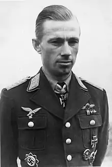 Black-and-white photograph showing the face and upper body of a young man in uniform. The front of his shirt collar bears Iron Cross decorations, black with light outline.