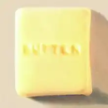 A photograph of a square of butter with the word "butter" carved into it in all caps.