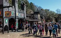 A group of costumed revelers walk past the castle-like entrance to the fair