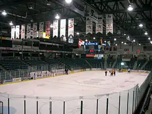 Photo of ice rink with team banners hanging from the ceiling