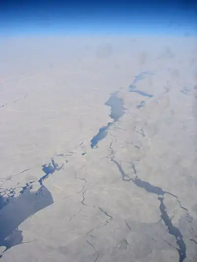 Aerial view of the Chukchi Sea between Chukotka and Alaska, displaying a pattern of leads. Much of the open water inside those leads is already covered by new ice (indicated by a slightly lighter blue color)(scale not available).