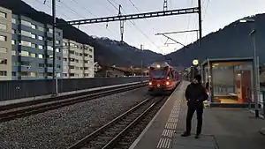 Train pulling up on single track with platform and shelter