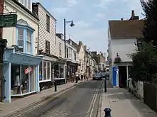 A narrow paved road, lined with shops