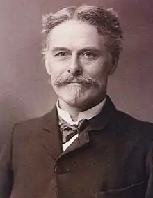 B & W photo/bust portrait of Edward Drinker Cope, paleontologist, c. 1895, in middle age with grey hair, mustache and chin puff; wearing a dark coat, soft bow tie and a slight smile.