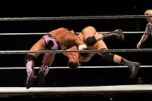 Two men in mid-air inside a wrestling ring.