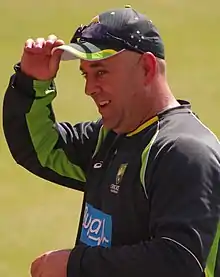 Picture of Lehmann wearing an Australian training jersey and holding a cap