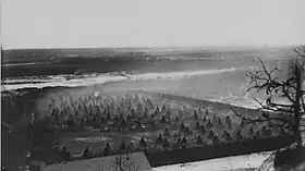 Black and white photo of one end of an island covered with hundreds of teepees inside a stockade