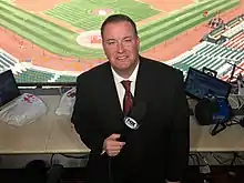 Dan McLaughlin in broadcast booth holding microphone