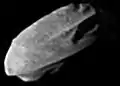 A small, irregularly shaped body elongated from the bottom left to top right. It is illuminated from the bottom left.