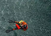 A rescue swimmer from Coast Guard Air Station Cape Cod, Massachusetts, is hoisted back into an HH-60 Jayhawk after retrieving a rescue training dummy.