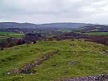 View from Dolebury Warren Hill Fort with remnants of stonework in the foreground. Crook Peak is shown in the background