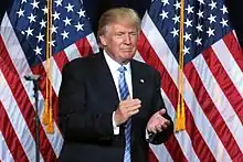 President Donald Trump clapping in front of U.S. flags