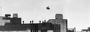 A monochrome picture of an aircraft, minus its tailplane and outer wing tips diving onto a rail station