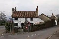 Street scene showing road junction and white painted house.