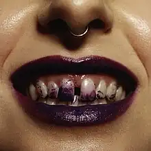 A close-up of a smiling mouth covered in purple lipstick